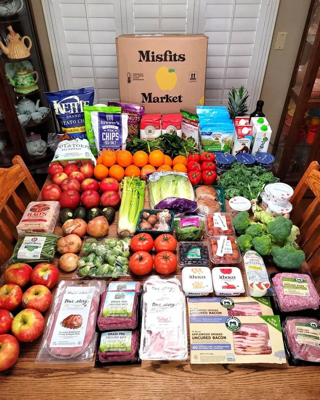 Misfits Market grocery ad example: a dining table covered in a delivered haul of produce, meat, and pantry goods