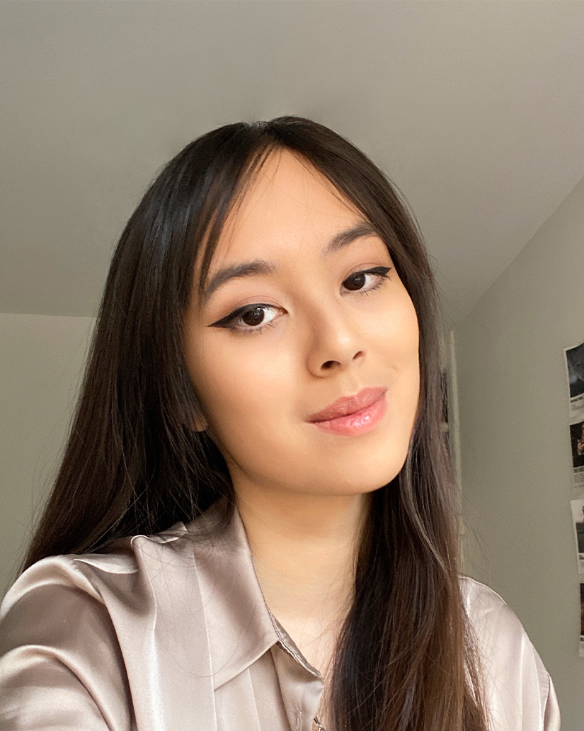 Glossier customer selfie UGC ad showing a young woman wearing winged eyeliner, glossy nude lip, and natural-looking Glossier makeup in a home setting with warm lighting
