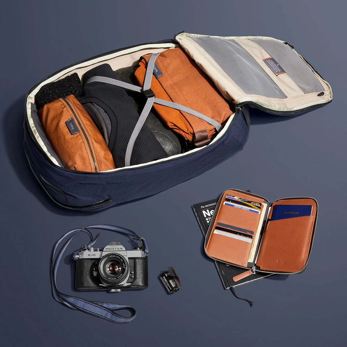 Bellroy travel organization products arranged in a top-down flat lay on a deep blue background