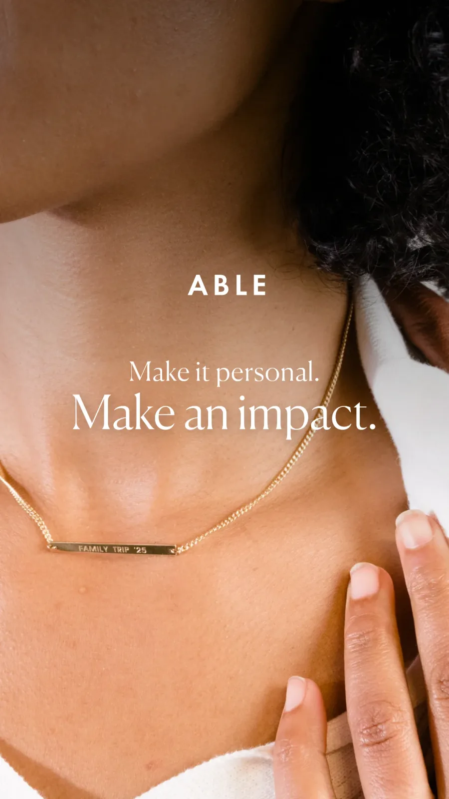 ABLE necklace ad: close crop of a collarbone with a gold bar necklace engraved "FAMILY TRIP '25", "Make it personal. Make an impact."
